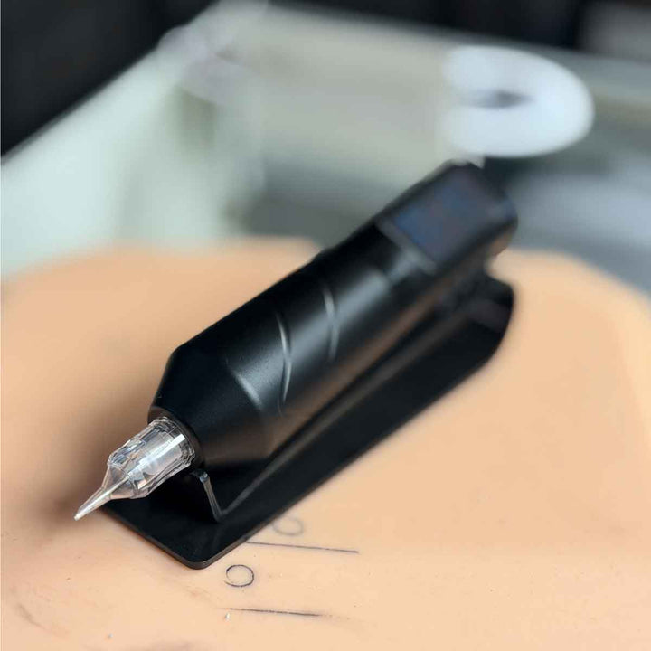 Black tattoo pen held on a person's arm with a blurred background