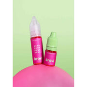 Two Brovi e-liquid bottles, one with a pink cap and one with a light green cap, standing on a pink sphere against a light green background.