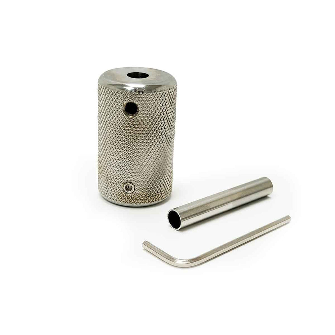 Stainless steel tattoo grip with a smaller cylindrical component and tool on a white background